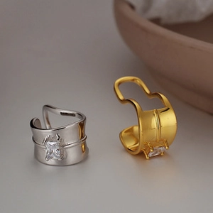 Detail of silver and gold wavy ear cuffs featuring a rectangular clear zircon inlay