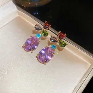 Detailed macro view of gold-plated drop earrings with multicolor gemstones in a jewelry box