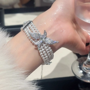 Gros plan d'un bracelet de perles à trois rangs avec pendentif oiseau en zircon