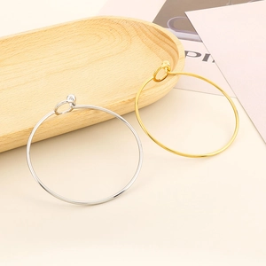Detailed view of minimalist gold and silver bangles with spherical clasp on a tray
