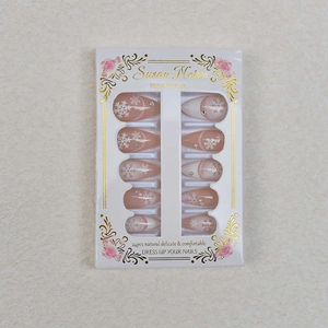 Detail of almond press-on nails with white snowflake prints and sparkling rhinestones