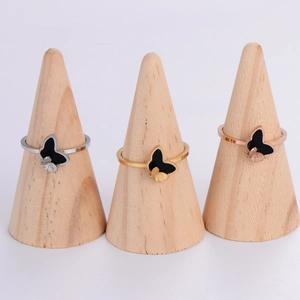 Three minimalist butterfly rings in silver, gold, and rose gold on wooden stands