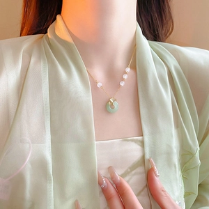 Détail du collier feuille de ginkgo dorée avec pendentif en jade vert sur un mannequin