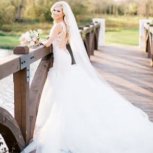 Elegant white mermaid wedding dress with lace floral back and a long flowing bridal veil