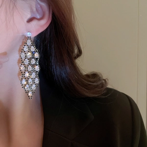 Close-up of elegant black metal earrings with tassel diamonds worn by a model