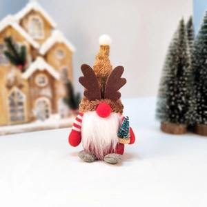 Christmas gnome ornament with antlers holding a mini tree in a snowy festive background