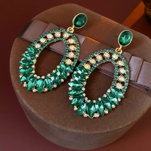 Detailed macro view of vintage emerald green rhinestone earrings on a velvet box