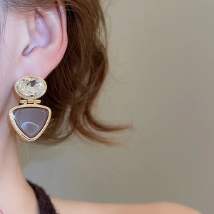 Close-up of 18k gold-plated geometric drop earrings with crystals on a female model