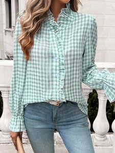 Detailed view of the green plaid blouse featuring ruffle trim and contrast buttons