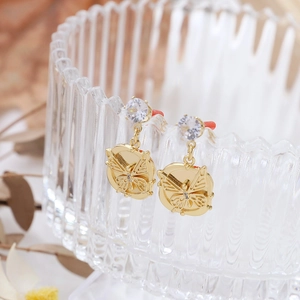 Detail of gold-plated butterfly charm earrings with zircon inlay on a glass edge