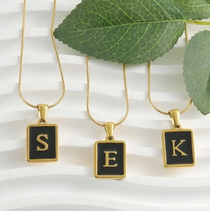 Détail de colliers chaîne serpent dorée 18k avec pendentifs rectangulaires noirs à lettres
