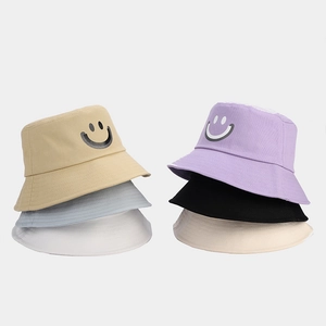Detail view of cotton bucket hats showing smiley face prints in six versatile colors