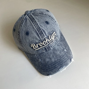 Detail of Brooklyn New York 3D embroidery on washed denim baseball cap with distressed holes