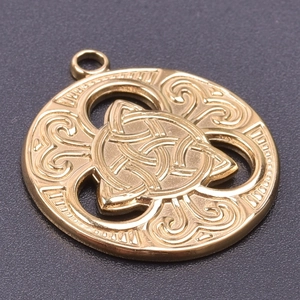 Macro shot of gold-plated stainless steel Triskele pendant with intricate relief details