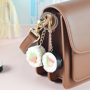 Portachiavi realistici in PVC con sushi e onigiri su borsa in pelle marrone vintage