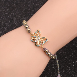 Macro shot of gold-plated butterfly bracelet with colorful zircons on braided cord