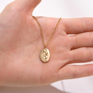 Macro view of gold stainless steel necklace featuring a vintage oval rose relief pendant
