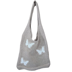 Dettaglio della borsa a tracolla in maglia beige con motivi a farfalla blu chiaro