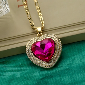 Macro shot of rose red heart pendant with zircon halo on golden Figaro chain
