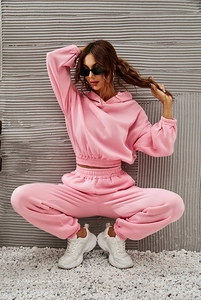 Pink cropped hoodie and high-waisted jogger set worn by a model in an industrial setting