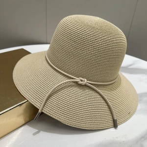 Détail d'un chapeau de soleil beige avec texture de paille et cordon en cuir décoratif