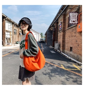 Detail of a large orange oxford cloth crossbody bag with adjustable wide strap for daily use