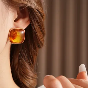Square amber resin earrings with gold edges worn in a stylish retro fashion look
