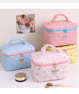 Close-up of quilted bow cosmetic bags in various colors with handle and zipper details