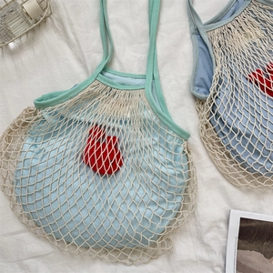 Nahaufnahme einer geflochtenen Netztasche mit blauer Innentasche und Kirsch-Anhänger