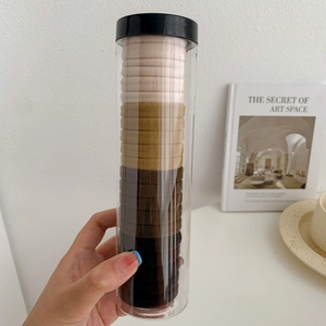 Close-up of elastic hair ties set in earth tones stored in a transparent plastic cylinder