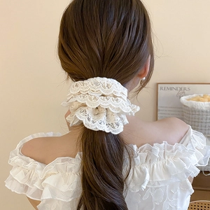 Gros plan d'un chouchou en dentelle blanche multicouche avec broderie florale sur queue