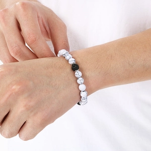 Close-up of white howlite and black lava stone beaded bracelet on model's wrist