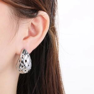 Macro shot of silver woven teardrop earrings on model showing metal texture and fit
