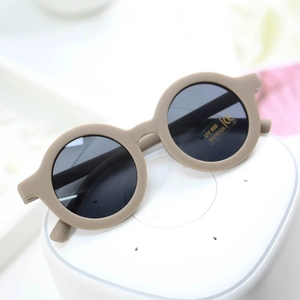 Detail of round matte khaki kids sunglasses with UV400 and CE protection labels