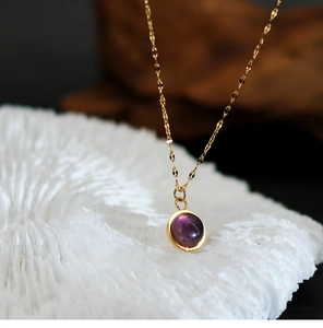 Macro shot of 18K gold plated necklace with round purple natural stone pendant detail