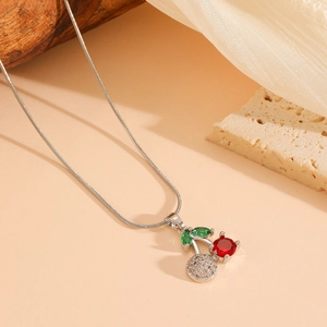 Detail of silver cherry necklace featuring red and green crystal pavé on snake chain