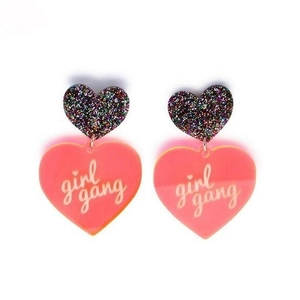 Pink glitter acrylic heart earrings featuring white girl gang script on white background