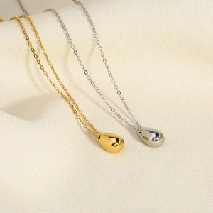Close-up of gold and silver water drop necklaces on elegant silk fabric background
