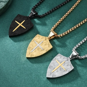 Vintage shield necklace with cross motif and bark texture in black, gold, and silver