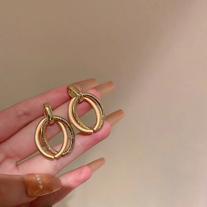 Nahaufnahme goldener ovaler Ohrringe mit matter und glitzernder Optik im Detail
