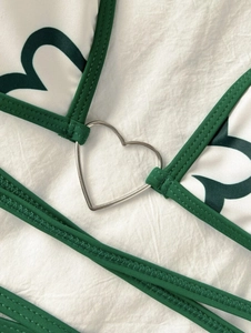 Détail macro d'une boucle en métal argenté en forme de cœur sur un bikini vert imprimé