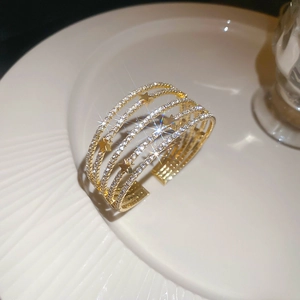 Bracelet multicouche doré avec strass et étoiles posé sur une assiette blanche en céramique