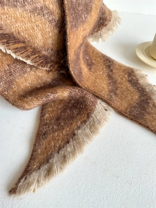 Gros plan sur la texture du foulard léopard avec franges et bougeoir beige décoratif