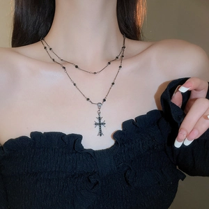 Dettaglio della collana doppia argentata con ciondolo a croce gotica e perline nere