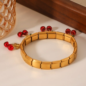 Detail view of gold stainless steel modular bracelet featuring vibrant red cherry charms
