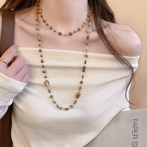 Close-up of multi-layer earthy beaded necklace with vintage stone and gold link details