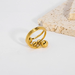 Dettaglio di un anello in titanio dorato a doppio strato con perle metalliche lucide