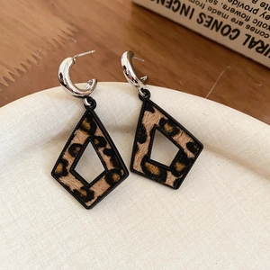 Vue détaillée de boucles d'oreilles géométriques léopard sur un plateau beige chic