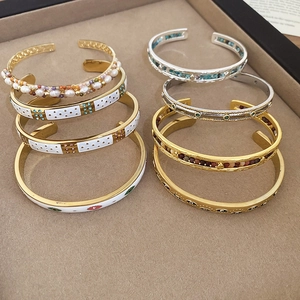Détail de bracelets ouverts dorés bohèmes avec perles, zircons et motifs œil porte-bonheur