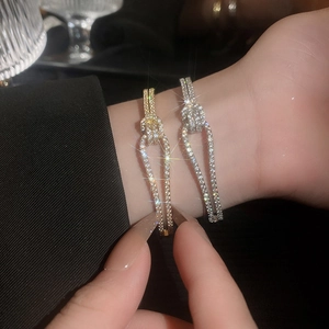 Detail van gouden en zilveren knooparmbanden met zirkonia kristallen op de pols
